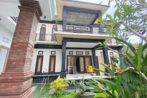 ein Haus mit einem Balkon und einer Backsteinsäule in der Unterkunft Capital O 93844 Arta Adi Homestay in Bangli