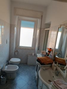 een badkamer met een wastafel, een toilet en een raam bij L'appartamento delle vacanze in Venturina Terme