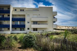 un bâtiment blanc avec des balcons bleus sur la plage dans l'établissement Charmant appartement en front de mer avec piscine, à Lacanau-Océan
