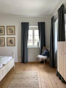 1 dormitorio con cama, ventana y silla en Zauberhaftes Haus in Ortenburg en Ortenburg