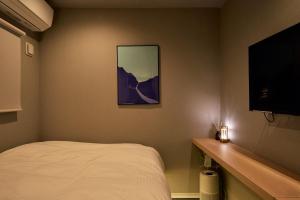 a bedroom with a bed and a flat screen tv at Boxi Hakata 1 -Sleep Hotel- in Fukuoka