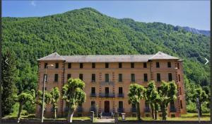 a large building with trees in front of a mountain at LA MARMOTTE appartement T2 classé 3 étoiles in Aulus-les-Bains