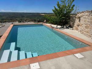 a swimming pool in front of a stone house at Castell de l'Aguda in Torá de Rulbregos