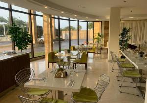 un restaurante con mesas y sillas blancas y ventanas en Eurobuilding Hotel & Suites Coro en Santa Ana de Coro