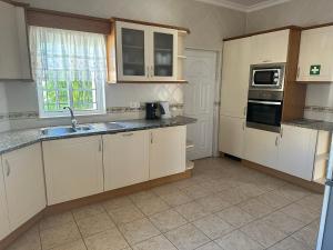 una cocina con armarios blancos y fregadero en Benvindo Villa en Albufeira