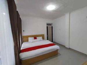 a bedroom with a bed with a red and white blanket at Ilfa Guest House syari'ah in Jatiwangi