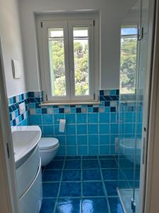 a blue tiled bathroom with a toilet and a sink at Villa Colle dei Pini in Cupra Marittima +23 photos