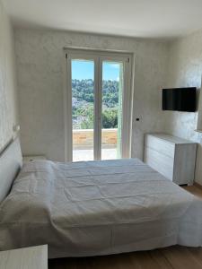 a white bedroom with a large bed and a window at Villa Colle dei Pini in Cupra Marittima