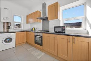 une cuisine avec des armoires en bois et une laveuse et une sécheuse dans l'établissement Central Reading - 3 bed apartment, à Reading