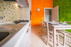 uma cozinha com um balcão e uma mesa com cadeiras em Avola house orange em Avola