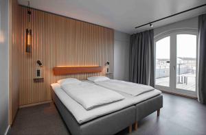 Zleep Hotel Køge في كوغ: سرير في غرفة مع نافذة كبيرة