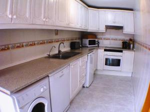 a white kitchen with white cabinets and a sink at Casa Ladera in Las Lagunas Mijas
