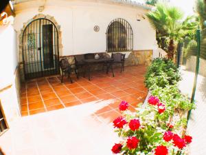 a patio with red flowers in front of a house at Casa Ladera in Las Lagunas Mijas