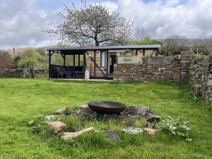 a garden with a stone building and a bowl in the grass at 1 Bed converted Railway Wagon near Crickhowell in Crickhowell