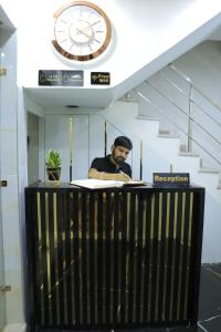 un hombre sentado en un escritorio con un reloj en las escaleras en Amritsar view new hotel near golden temple, en Amritsar