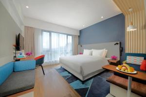 Holiday Inn Express Qingdao Chengyang Central by IHG في تشينغداو: غرفة بالفندق سرير وطاولة مع صحن فاكهة +37 صورة
