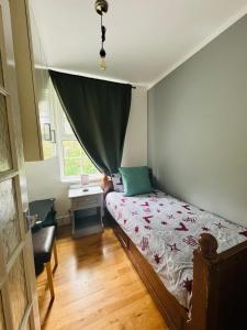 3 bed West Norwood Apartment في West Dulwich: غرفة نوم بسرير ومكتب ونافذة