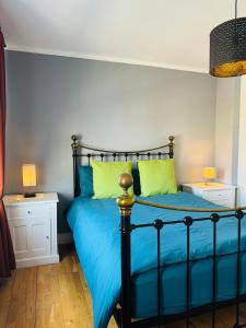 3 bed West Norwood Apartment في West Dulwich: غرفة نوم بسرير وملاءات زرقاء ووسائد خضراء