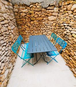 une table de pique-nique et deux chaises devant un mur en pierre dans l'établissement Appartement climatisé avec extérieur à Sarlat, à Sarlat-la-Canéda