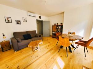 ein Wohnzimmer mit einem Sofa und einem Tisch in der Unterkunft Appartement climatisé avec extérieur à Sarlat in Sarlat-la-Canéda