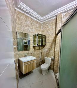 a bathroom with a toilet and a sink and mirror at Welltima Teranga in Dakar