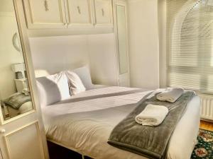 een witte slaapkamer met een bed met twee handdoeken erop bij Marina Waves, free parking, patio, ground-floor in Brighton & Hove