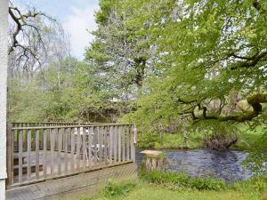 una terraza de madera con mesa y sillas junto a un río en River Cottage, en Enochdhu