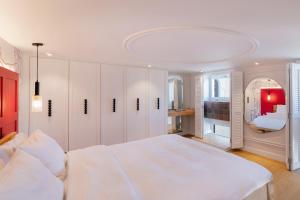 a white bedroom with a large bed and a mirror at Agora Suites in Athens