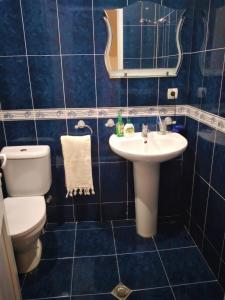 a blue tiled bathroom with a toilet and a sink at Izi's cozy apartment in Kutaisi +17 photos