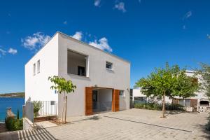 una casa blanca con árboles frente al agua en Villa CapeCarol, en Rogoznica