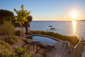 un patio con sillas y una piscina junto al agua en Villa CapeCarol, en Rogoznica