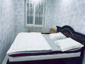 1 dormitorio con 1 cama con sábanas blancas y ventana en Yunusabad 15, Tashkent, en Tashkent