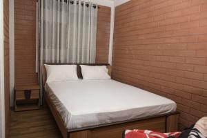 Habitación pequeña con cama en una pared de ladrillo en Grashia Guest, en Nuwara Eliya