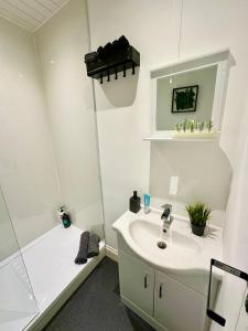 a white bathroom with a sink and a shower at Cosy stylish Dumbarton flat in Dumbarton