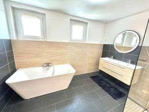 La salle de bains est pourvue d'une baignoire, d'un lavabo et d'un miroir. dans l'établissement Luxurious cozy house 10 minutes from Charles de Gaulle Airport, à Tremblay-en-France
