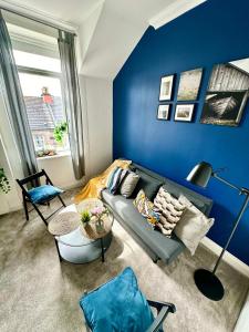 a living room with a couch and a blue wall at Cosy stylish Dumbarton flat in Dumbarton