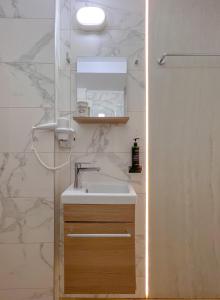 La salle de bains est pourvue d'un lavabo, d'un miroir et d'une douche. dans l'établissement Aurora Rooms - 290m from Aqua Park, à Băile Olăneşti