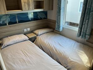 twee bedden in een kleine kamer met een raam bij Rockley Park Private Holiday Homes in Poole