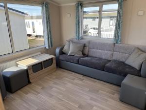 a living room with a gray couch and windows at Rockley Park Private Holiday Homes in Poole