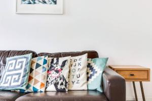 ein Wohnzimmer mit einer braunen Couch mit Kissen in der Unterkunft GuestReady - Beautiful Home in Wimbledon Village in London