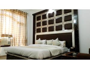 a bedroom with a large bed with a large headboard at Hotel Kerni Palace, Katra in Katra