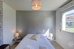 a white bedroom with a bed and a window at Le Dahlia / Jardin Botanique in La Riche