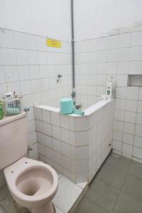 a bathroom with a toilet in a white tiled room at OYO 93869 Regina Homestay Syariah in Surabaya