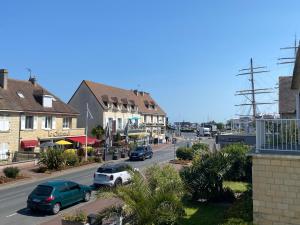 a street in a town with cars parked on the road at Le Cabieu in Ouistreham
