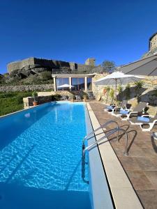 a swimming pool with chairs and a house at Casa do Penedo Castle House in Linhares