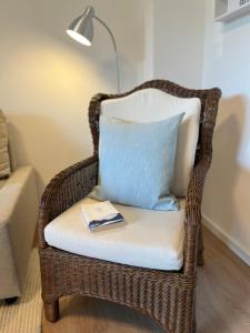 a wicker chair with a pillow and a book on it at NEU 2024 - Fewo mit Meerblick & Flair in Harrislee