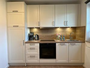 a kitchen with white cabinets and a sink at NEU 2024 - Fewo mit Meerblick & Flair in Harrislee