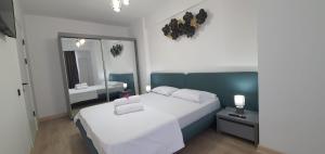 una camera da letto con un grande letto bianco e uno specchio di Infinity Aparthotel & Spa Resort Prima Linie la Mare, Piscina Infinity la Etaj 11 Panorama a Mamaia Nord - Năvodari