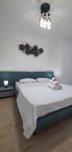 - une chambre avec un lit blanc et un lustre dans l'établissement Infinity Aparthotel & Spa Resort Prima Linie la Mare, Piscina Infinity la Etaj 11 Panorama, à Mamaia Nord – Năvodari
