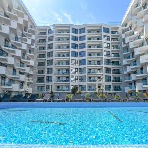 un grand immeuble avec une piscine en face de celui-ci dans l'établissement Infinity Aparthotel & Spa Resort Prima Linie la Mare, Piscina Infinity la Etaj 11 Panorama, à Mamaia Nord – Năvodari